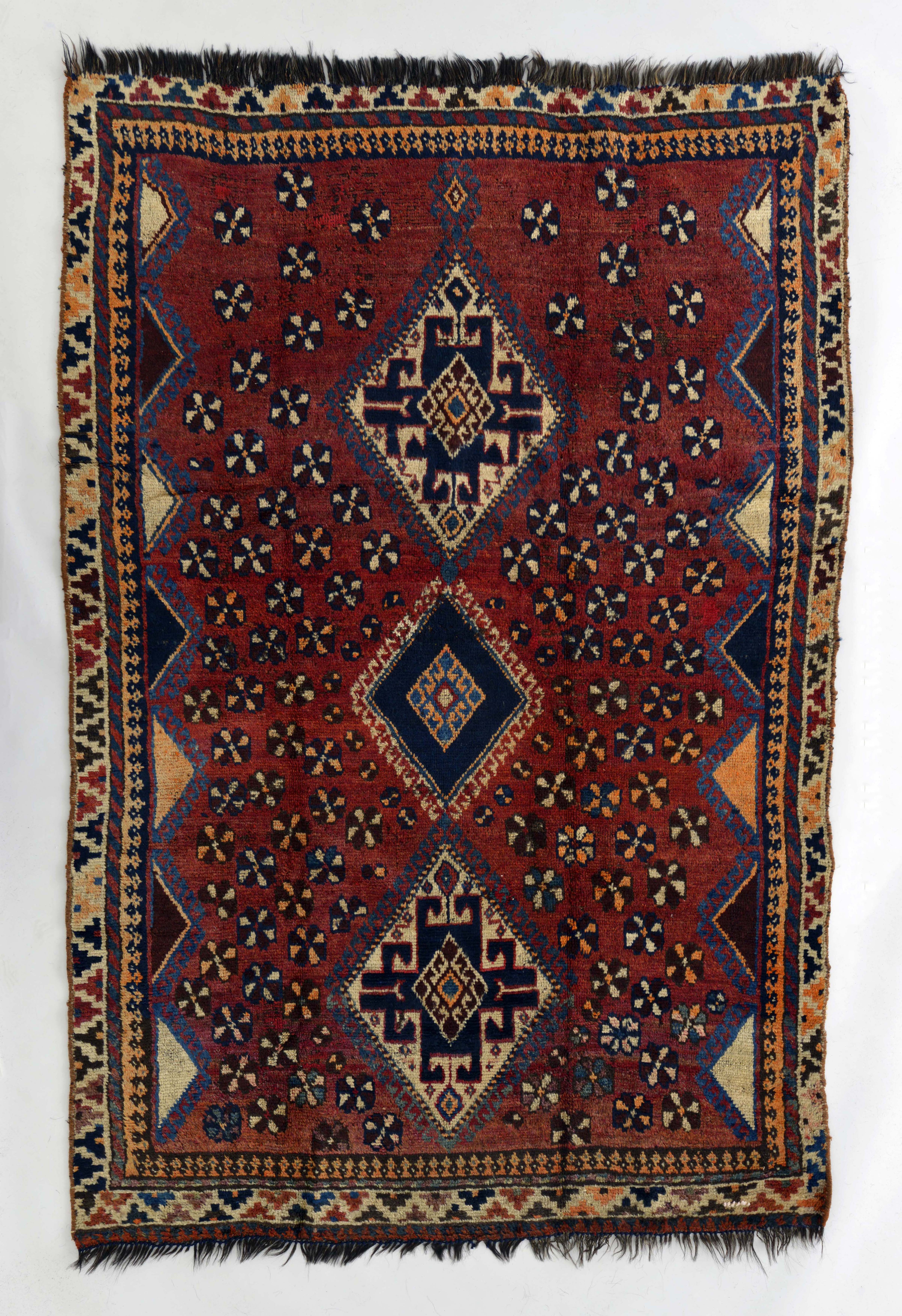南イラン　カシュガイ族　1920年頃　羊毛・黒山羊毛　210×148cm　カシュガイ族を象徴する三つのメダリオンが核となった古い絨毯です。縦糸には黒山羊の毛が使われ、長い年月の使用に耐えられる強靭さを備えています。
