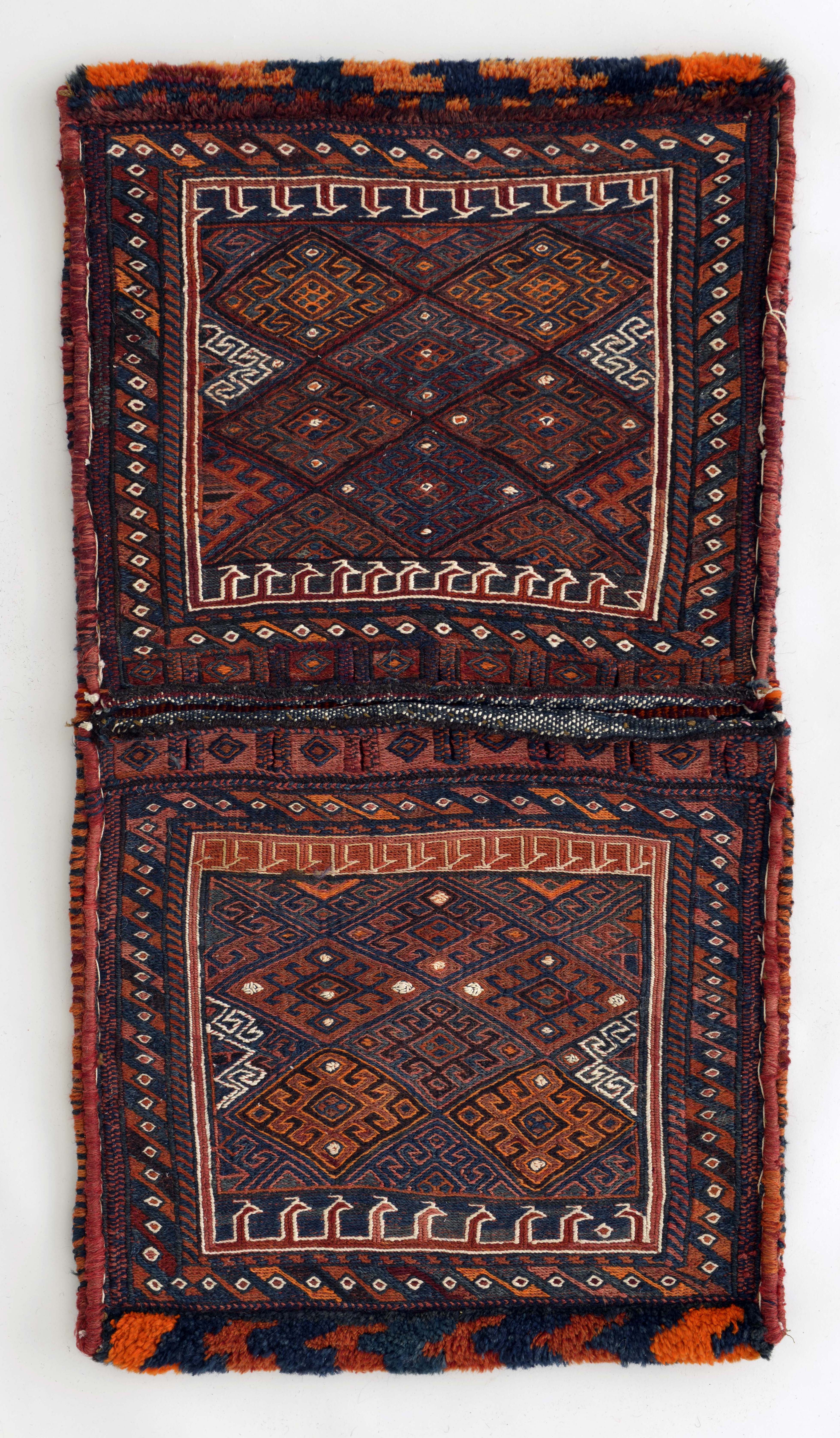 鞍袋（ホリジン）　西イラン　ルリ・バクティアリ族　1950年頃　羊毛　100×53cm　四角い囲みの内側・上下に白いラインで描かれているモチーフは動物の頭とされています。高度で緻密な織り技法で仕上げられています。