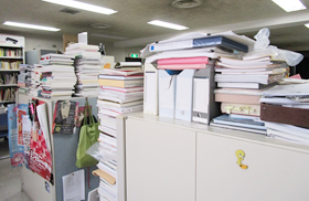 誰の机かは言えません…。絶妙なバランスで積まれています。